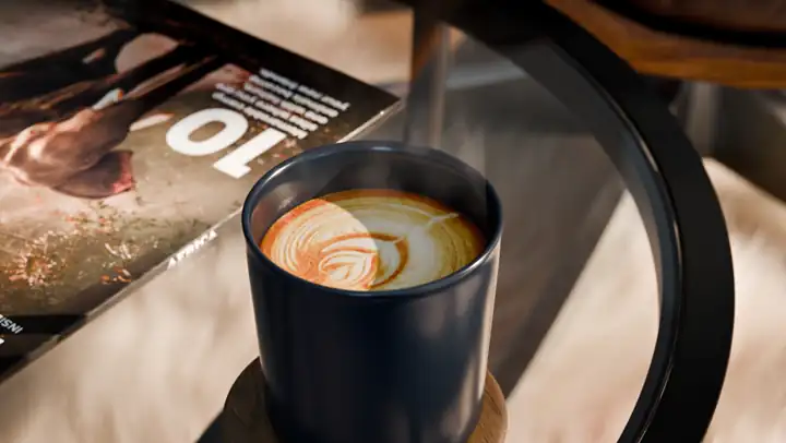 Close on a cup of coffee with latte art beside a magazine